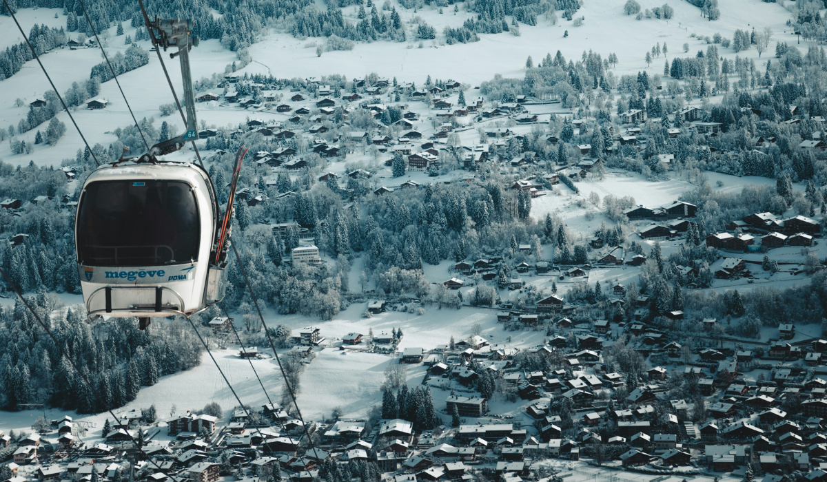 View of the village in the valley, with a cable car suspended reading Megeve.