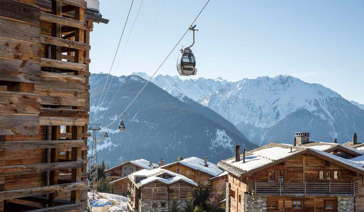 Cable car suspended above the village chalets and mountains in the background.