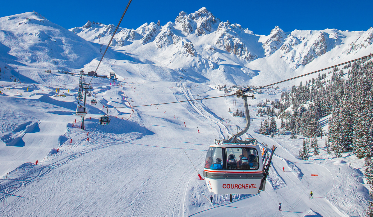 Snow covered mountains scene, with cable car reading "Courchevel" on the side and a wide open piste with no one skiing in it.