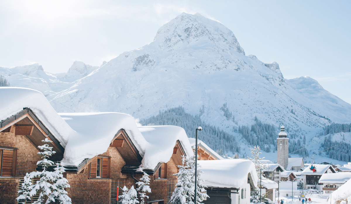 Village scene of Lech, with snow covered chalet rooves, and iconic snow covered mountain in the background.