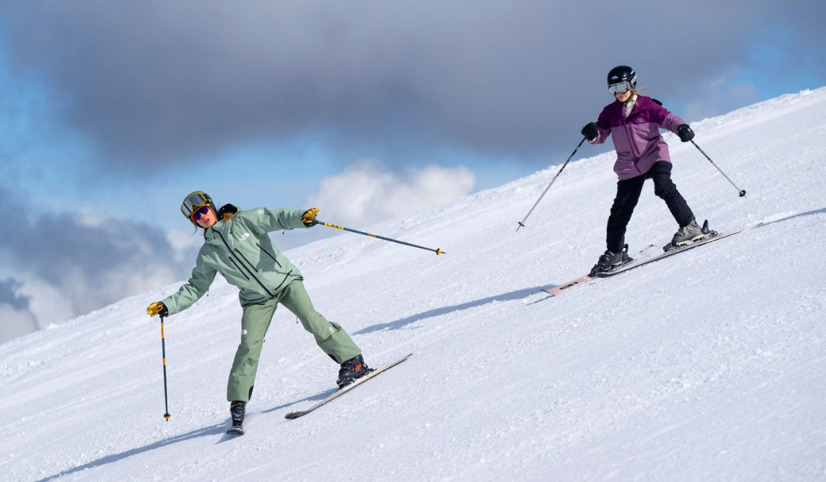 Ski guide teaching an adult beginner skier how to turn down the slope.
