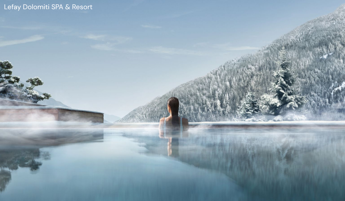 Lady in the outdoor heated pool looking out over the snow covered alpine trees.
