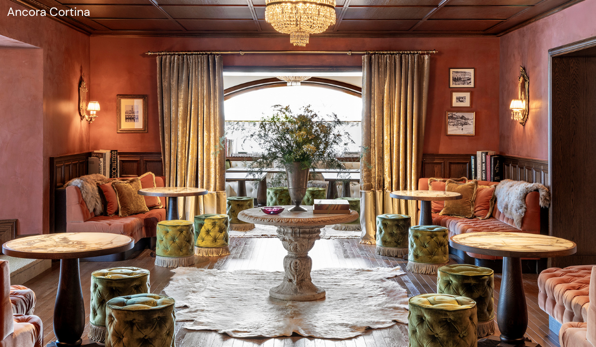 warm, dark muted pink interior, soft seating with an ornate round table in the middle with flowers on it.