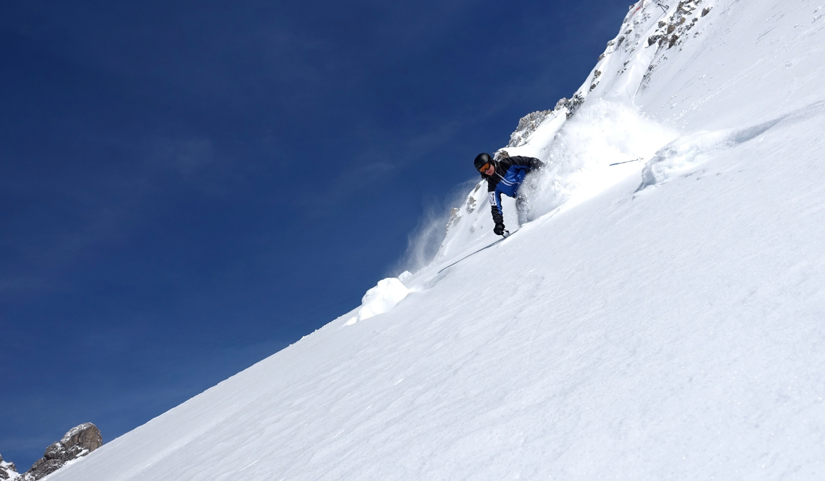 mid-close shot of a skiier skiing up powder as they decent an off-piste slope.