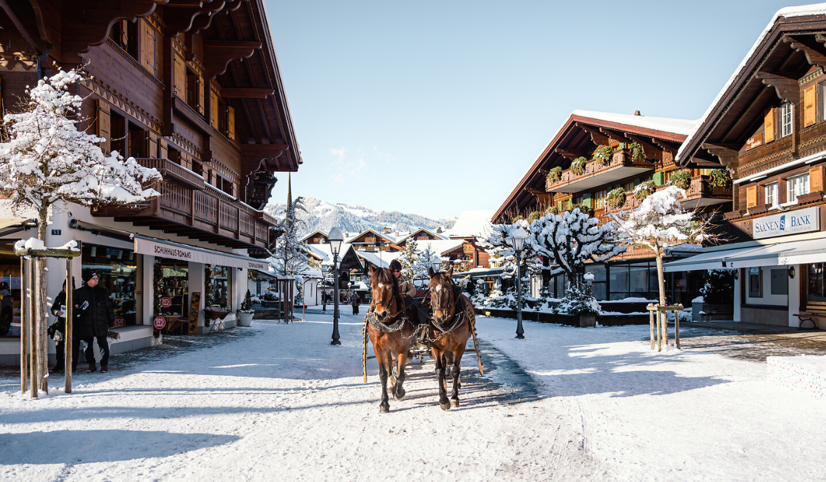 Horse drawn carriage on a snowy street with traditionl chlelet buildings either side.