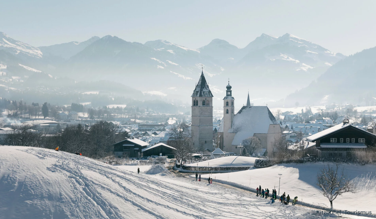 Snowy scene of church spires in background and little village in the valley.