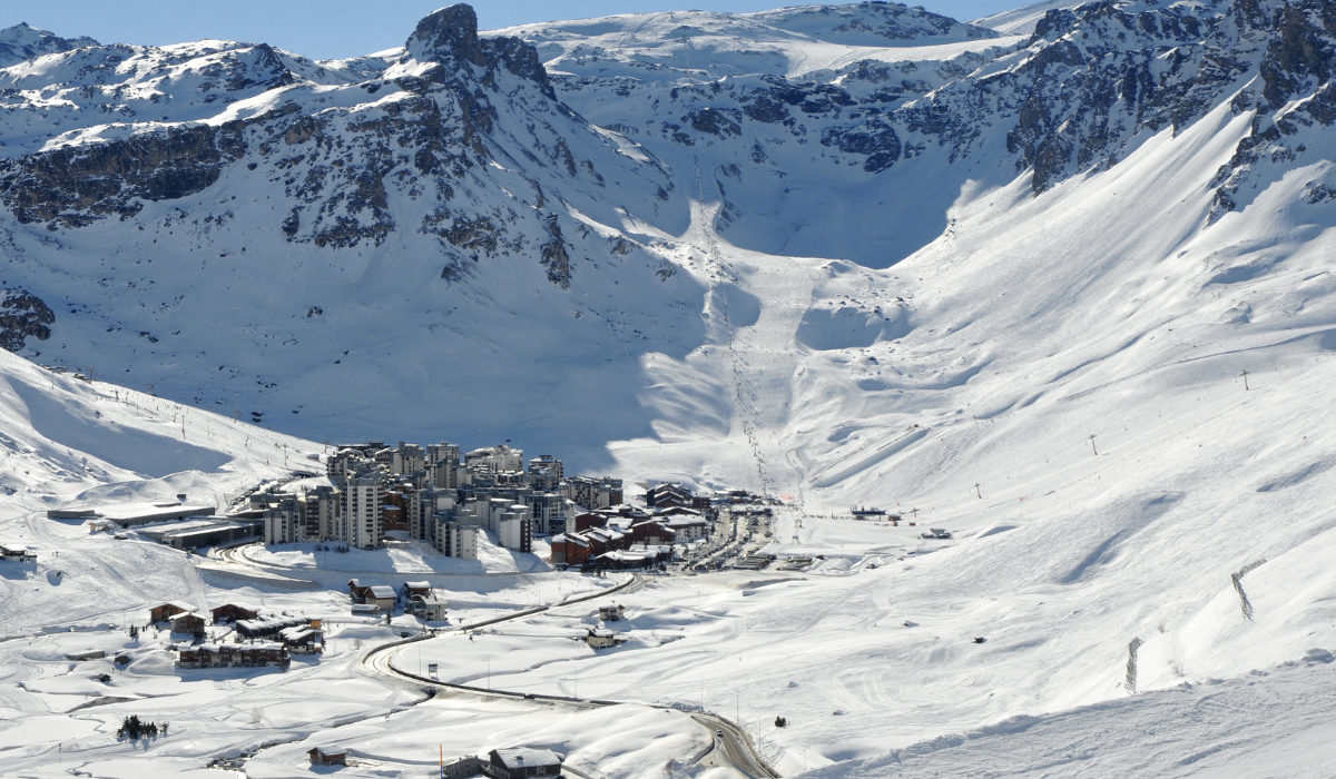 bowl like valley with buildings in the middle, surrounded by snow and mountains.