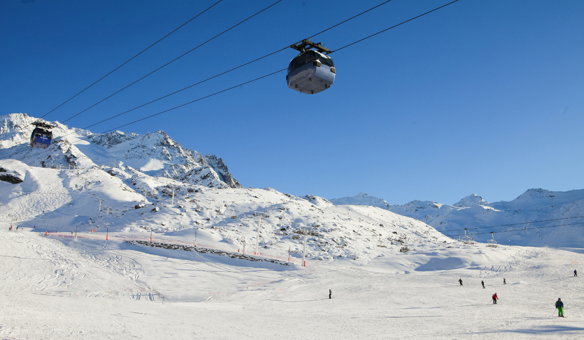 skiable area, with a cable car suspended above, pure blue skies.