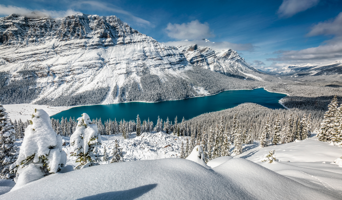 pristine snow, and mountains with a blue lake in the mid-ground.